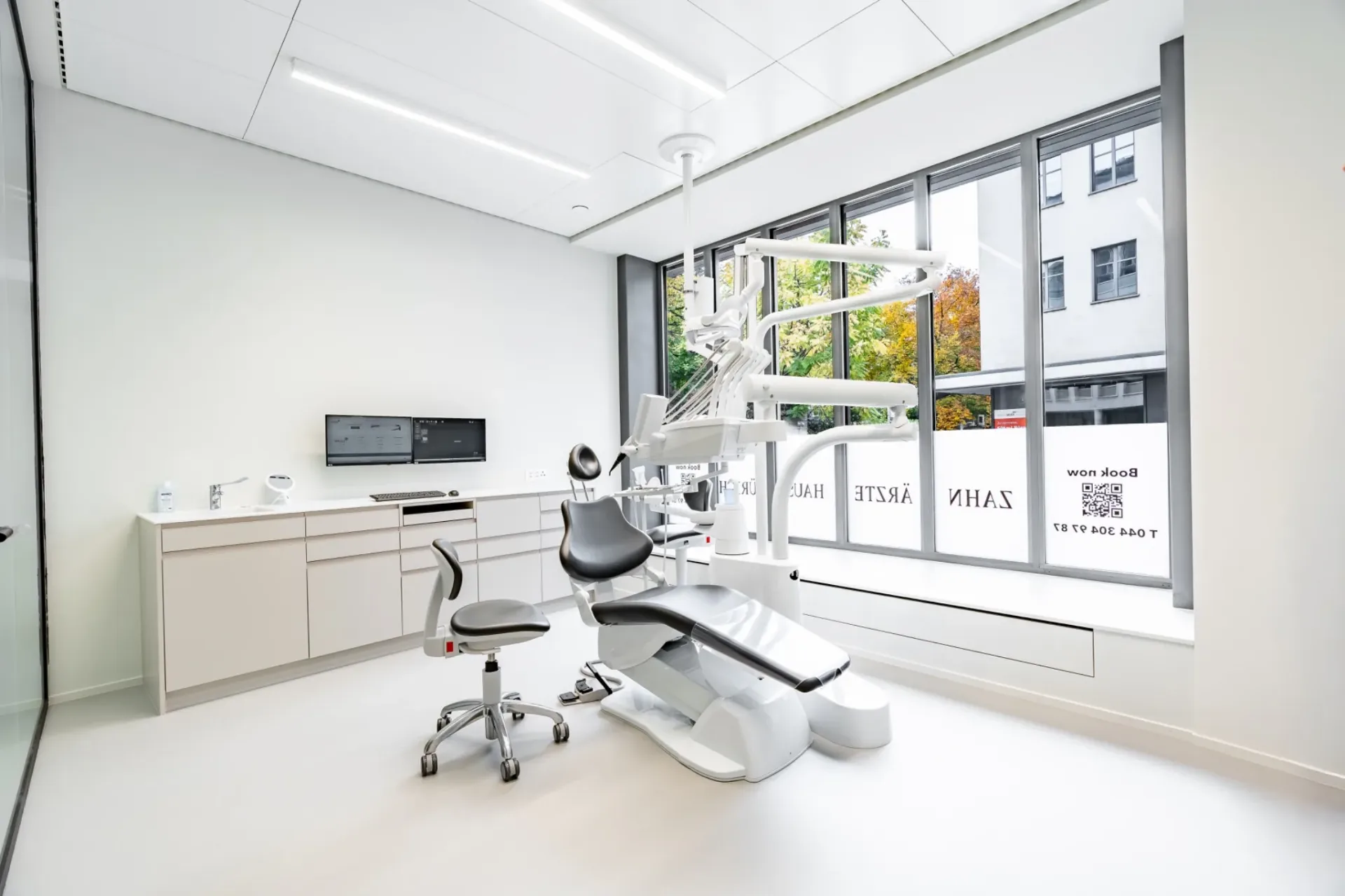 Behandlungszimmer im Zahnärztehaus Zürich mit modernem Behandlungsstuhl und großen Fenstern