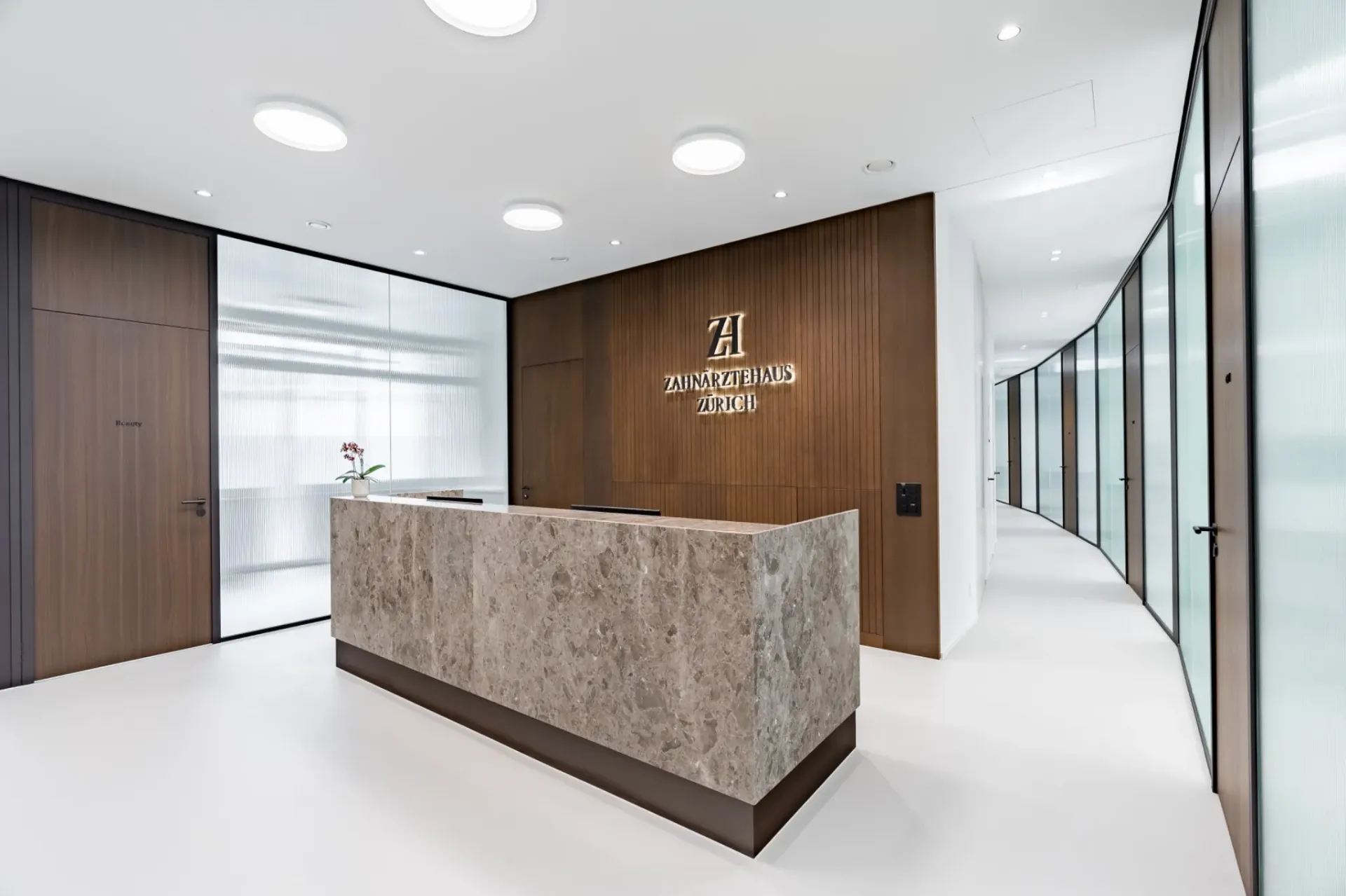 Rezeption im Zahnärztehaus Zürich mit Blick in den Flur und Glasfronten